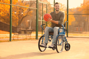 Young man in wheelchair with ball on playground