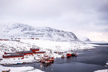 Fishing boats and harbor buildings with mountains in the background, port of Nuuk, Greenland