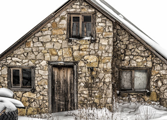 An old abandoned stone house covered with snow.