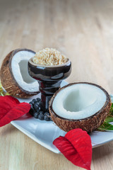 Shisha coconut in glossy black cup on a plate with opened coconut