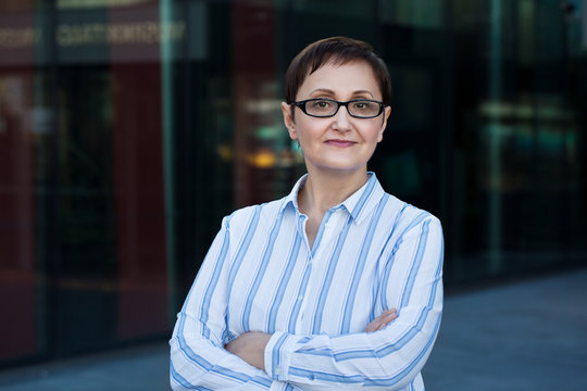 Older business woman headshot. Close-up portrait of executive, teacher, principal, CEO. Confident and successful middle aged woman 40 50 years old wearing glasses and shirt.