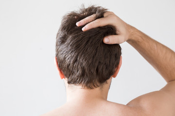 Man touching his brown hair on the gray background. Cares about a healthy and clean hair. Beauty...