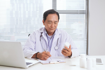 Fototapeta na wymiar Portrait of senior doctor sitting at his desk in medical office