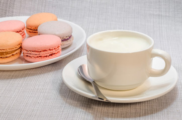 Fototapeta na wymiar Cake macaroon on the plate and a frothy coffee, close up