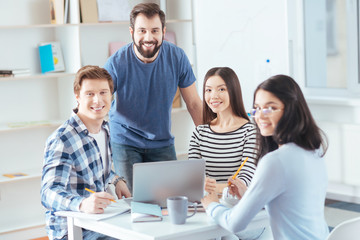 Successful startup. four colleagues cooperating on project while smiling  and looking at the camera