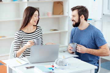 Obraz premium Coffee break. Merry play two colleagues looking at each other and laughing while drinking coffee 