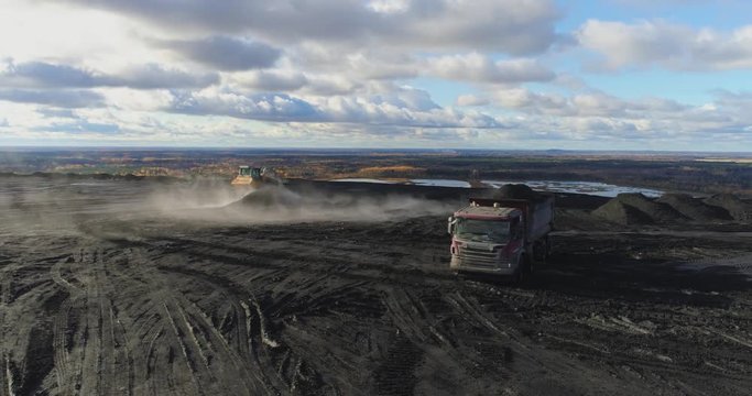 Aerial footage of big red truck in a career of mining. Delivery by the motor transport from a pit. Aerial footage.