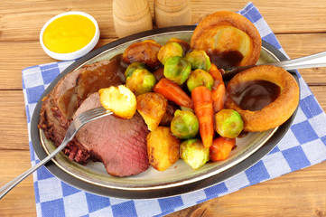 Traditional English roast beef meal with roasted potatoes, vegetables and Yorkshire puddings
