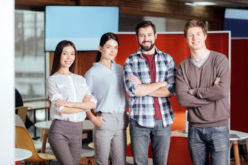 Fototapeta premium Business difficulties. Cheerful joyful four colleagues standing next to each other while looking at the camera and grinning