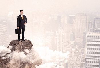 Happy businessman standing on stone top