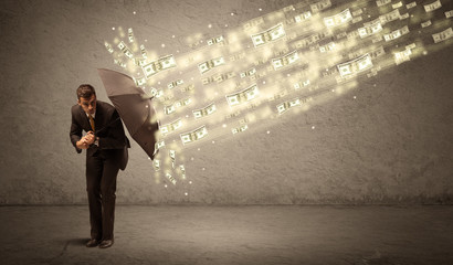 Business man holding umbrella against dollar rain concept