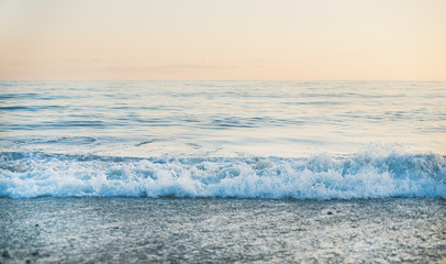 Mer calme et vue sur la plage de galets au coucher du soleil, couleurs pastel