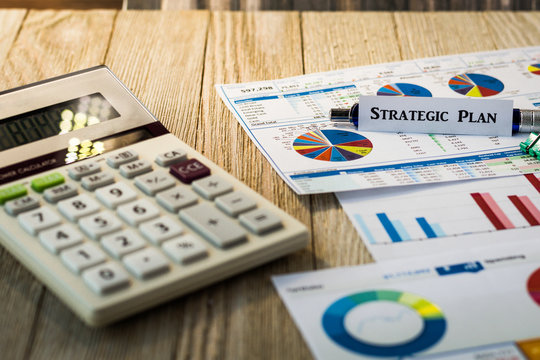 Strategic Plan motivational finance investment concept with charts and graphs and calculator on wooden board