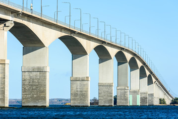 Concrete bridge over water. Gray pillars support the weight of the structure. Vital part of infrastructure and link the island of Oland to mainland Sweden. - 187447118