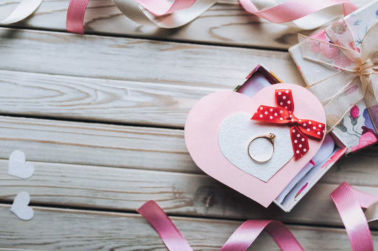 Marriage proposal concept. A wedding ring on a gift box on a wooden background. Valentine's Day. Copy space. Top view.
