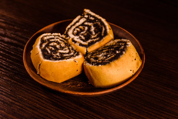 Ceramic plate with poppy seed buns on dark wooden table