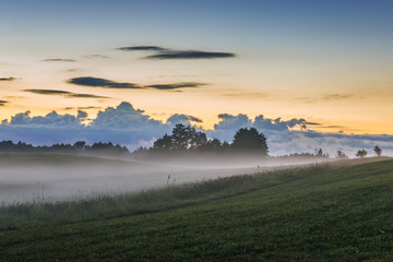 Late evening fog rising over fields near Jeziorowskie village, Masuria region of Poland