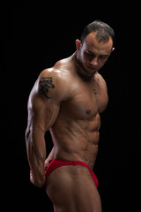 Fototapeta premium High level bodybuilder demonstrating bodybuilding stage positions. studio shot of male fitness model with trained relief body.