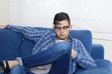 Obraz premium young casual in the home sofa with mobile phone