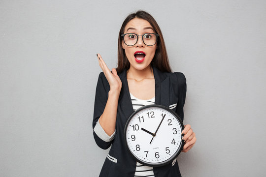 Surprised Asian Business Woman In Eyeglasses Holding Clock