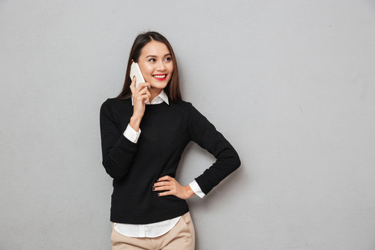 Smiling asian woman in business clothes with arm on hip