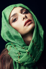Close-up studio portrait of attractive east woman with beautiful dark eyes, big lips and birthmark near lips, wearing green hijab.