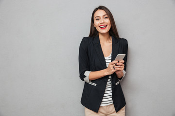 Happy asian business woman holding smartphone and looking at camera