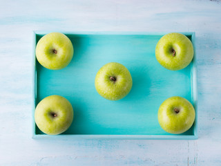 Green apples frame on turquoise tray. Healthy food concept