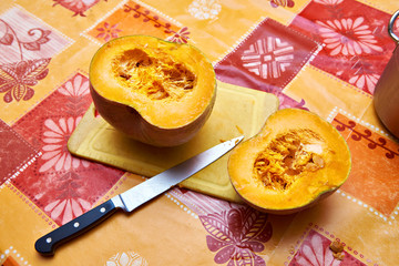 Two halves of pumpkin on table and kitchen knife