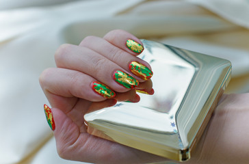 A bright manicure with gold and green glitter on the nails. Hand care and for yourself. Beauty for...
