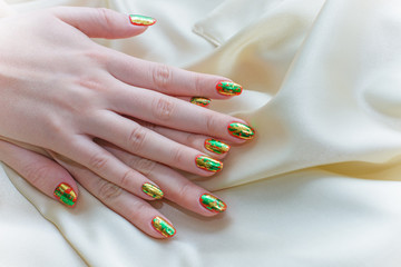 A bright manicure with gold and green glitter on the nails. Hand care and for yourself. Beauty for...