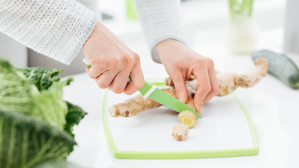 Woman cutting a fresh ginger root