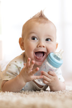sweet baby holding bottle with water and smiling