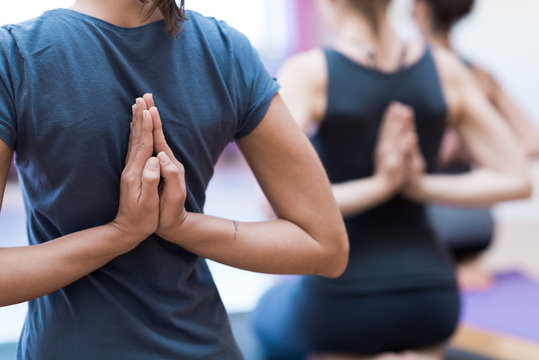 Women practicing yoga: reverse prayer pose
