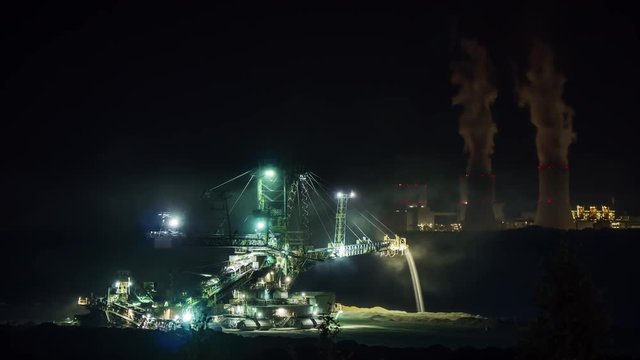 Coal digger with coal fired power plant in the background at night timelapse