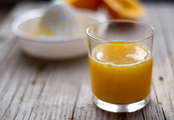 Fresh orange juice with squeezer and oranges on a side