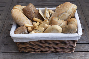 Assorted bread in a basket in a rustic wooden background