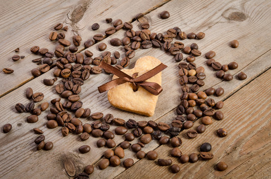 Frame- heart from coffee beans and two cookies-heart related together inside it on  wooden table