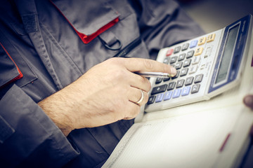Young worker. Focus on mans hand at calculator.