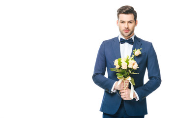 portrait of stylish groom in suit with wedding bouquet isolated on white