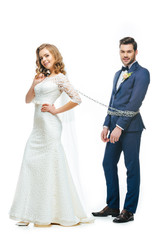 Fototapeta na wymiar young bride holding groom on chain isolated on white