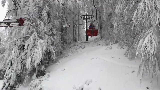 December 2017, Abetone, Italy - Going up on a chair lift in mountains in the middle of snowy wood
