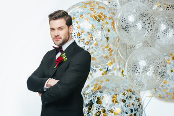 portrait of groom with arms crossed and balloons isolated on white
