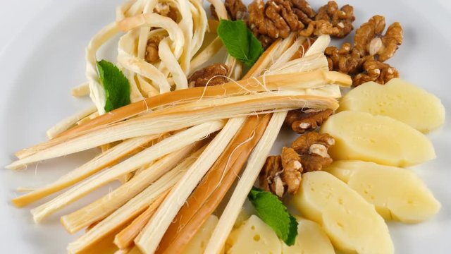 Cheese plate, including smoked chechil, suluguni and walnuts, loop, 4K, ProRes codec, 422 HQ