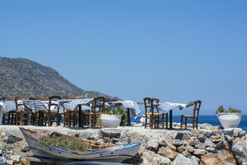 Many tables and chairs of the beautiful street restaurant on Crete in the sunny day near the sea