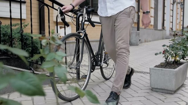 Slow motion video of young man walking with black vintage sport bicycle