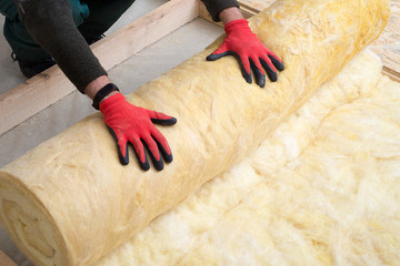 Caucasian Construction Worker with Roll of Insulating Material, Floor Insulating by Mineral Wool.