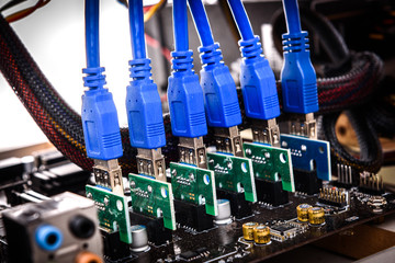 Cryptocurrency mining rig PCIe riser extenders plugged to motherboard.