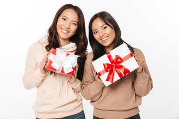 Fototapeta premium Two asian cute ladies sisters holding gift boxes surprise.
