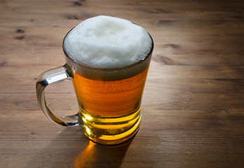 Glass of golden beer on wooden background.